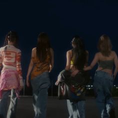 four girls walking down the street at night with their backs turned to the camera,