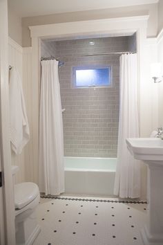 a bathroom with a toilet, sink and bathtub next to a window in the wall