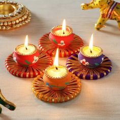 colorful candles are sitting on a table with an elephant figurine in the background