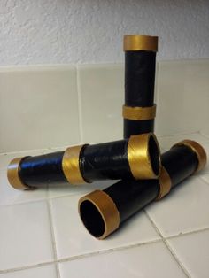 three black and gold pipes sitting on top of a white tile floor