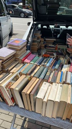 an open trunk filled with lots of books on top of a table next to a parked car