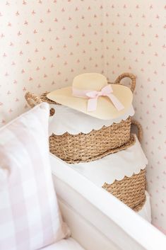 three baskets stacked on top of each other in a room with pink and white wallpaper