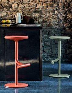 two stools sitting next to each other in front of a table with a cup on it