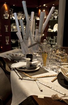 the table is set with glasses, silverware and candles