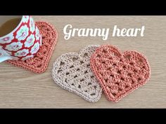 two crocheted heart coasters sitting on top of a table next to a cup