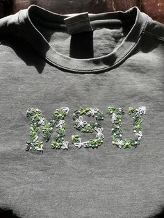 a grey tshirt with green and white flowers on it that says, mom