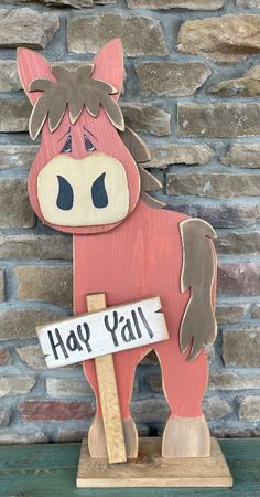 a wooden toy horse holding a sign that says hay y'all