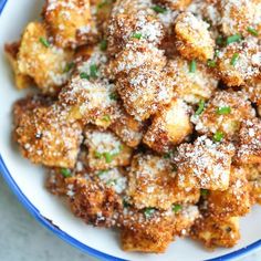 a white bowl filled with fried food covered in powdered sugar and parmesan