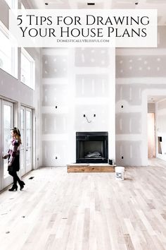 a woman walking through a large room with white walls and wood flooring in it