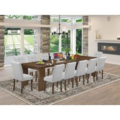 a dining room table with white chairs and an area rug in front of the fireplace