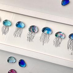 a group of jellyfish sitting on top of a white wall next to blue and purple stones