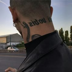 the back of a man's head with tattoos on his neck and behind him