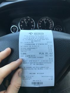 a person holding a ticket in their hand while sitting in the driver's seat of a car