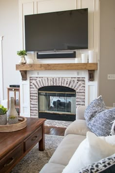 a living room with a fireplace and television mounted on the wall above it's mantle