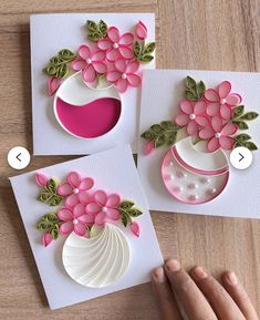 handmade greeting cards with pink flowers and green leaves on white paper, one being held by the other