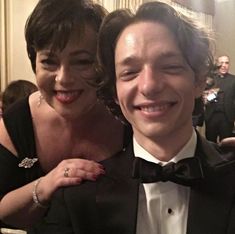 a man in a tuxedo poses for a photo next to a smiling woman