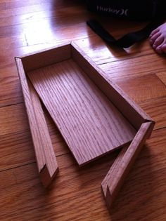 a wooden box sitting on top of a floor next to a person's feet