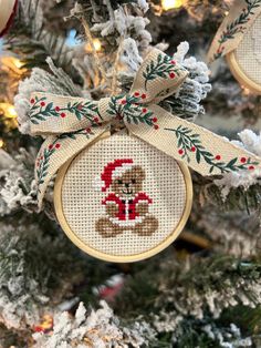 a cross stitch christmas ornament hanging from a tree