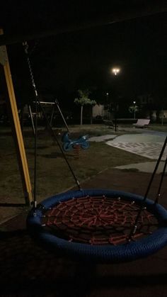 a tire swing in the middle of a playground at night with lights shining on it