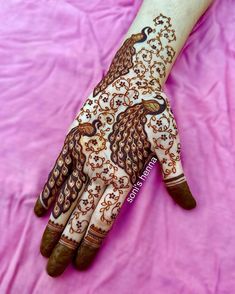 the hand is decorated with henna designs on pink fabric and it looks like an intricate bird