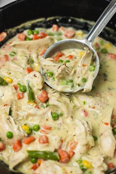 a ladle scooping out some chicken and vegetable soup from a skillet on the stove