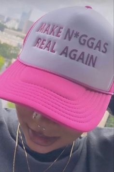 a person wearing a pink and white hat with the words make n'nggas real again on it