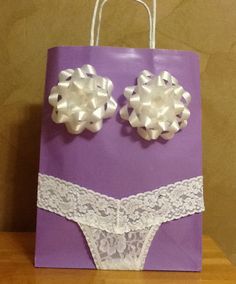 a purple paper bag with white lace and two large bows on the front, sitting on a wooden table