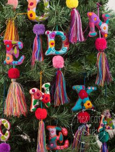 a christmas tree with colorful ornaments hanging from it's branches and the word joy spelled out