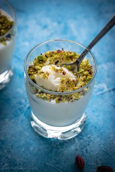 two glasses filled with yogurt, granola and pistachio toppings