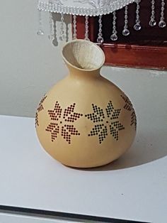 a small vase sitting on top of a white counter next to a chandelier