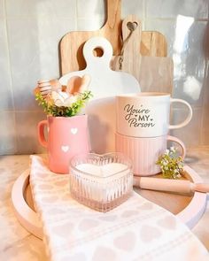 two coffee mugs sitting on top of a table next to a cutting board and knife