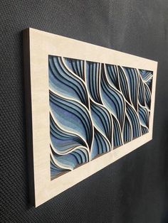 an art piece hanging on the wall next to a black door with blue and white swirls