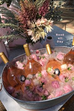 four bottles of rose wine in ice bucket with flowers