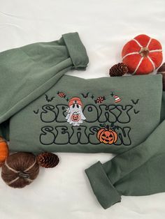 a green sweatshirt with the words sleepy halloween on it and pumpkins around it, along with other items