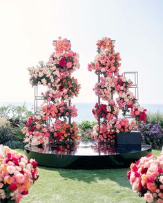 an outdoor ceremony with flowers on the ground and in the background, there is a circular table