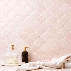 a bathroom with pink tiles and white towels on the counter next to a soap dispenser