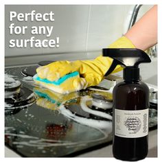 a person cleaning a stove top with a sponge and rag on it, next to a bottle of cleaner