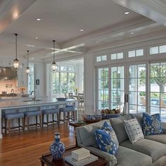 a living room filled with furniture next to an open kitchen and dining room area on top of a hard wood floor