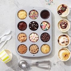 an assortment of cupcakes and muffins on a tray with spoons