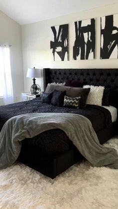 a black and white bedroom with two paintings on the wall above the bed, along with rugs