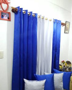 blue and white drapes are hanging in the corner of a room with two pillows