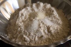 a metal bowl filled with flour on top of a stove