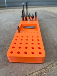 an orange tool holder with screwdrives and other tools in it on the ground