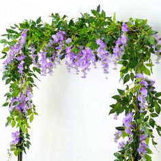 purple flowers are growing on the side of a white wall with green leaves and branches