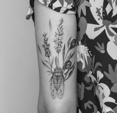 a black and white photo of a woman's arm with a bee tattoo on it