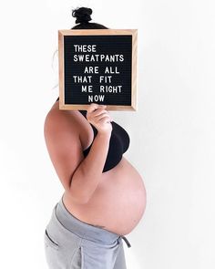 a pregnant woman holding up a sign that says, these sweatpants are all that's right now