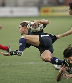 a group of people playing soccer on a field with one person falling to the ground