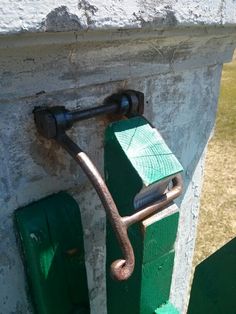 an old metal handle is attached to the side of a stone building with green paint