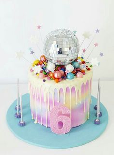 a birthday cake with a disco ball on top and decorations around the base for an age six