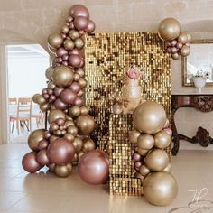 there is a gold and pink decoration in the room with balloons on the wall behind it